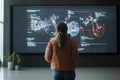 Standing in front of a massive digital display analyzing complex data patterns in a modern, high-tech environment