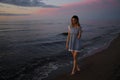 Standing full height: Portrait of a Beautiful blonde woman in a light blue dress on the Baltic Sea beach during sunset Royalty Free Stock Photo