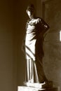 Standing goddess Athena. Marble statue in contrasting light. Close-up, sepia