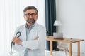 Standing and holding stethoscope. Professional medical worker in white coat is in the office Royalty Free Stock Photo