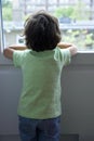 Standing lonely little boy looking out of the window Royalty Free Stock Photo