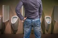 Standing man peeing to a urinal in restroom Royalty Free Stock Photo