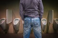 Standing man peeing to a urinal in restroom Royalty Free Stock Photo