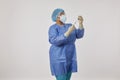 Standing nurse in a coverall PPE uniform against coronavirus holding the COVID-19 vaccine and a syringe Royalty Free Stock Photo