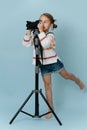 Standing on one foot little girl in striped sweater looking in a digital camera