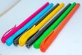 Standing Out From The Crowd Concept. Bunch of assorted multi colored boll point pens in rainbow arrangement on white background, Royalty Free Stock Photo