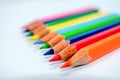 Standing Out From The Crowd Concept. Bunch of assorted multi colored pencils crayons in rainbow arrangement on white background,