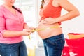 Standing pregnant women and midwife measuring circumference of b