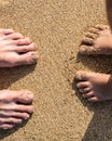 Standing on the sand looking down at feet, a child and father at the beach