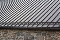 Standing seam modern metal roof over vintage stone wall Royalty Free Stock Photo