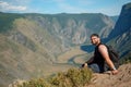 Standing sporty man with backpack on the mountain peak and beautiful mountains atbright sunny day. Royalty Free Stock Photo