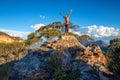 Standing at the top of a rocky cliff arms outstretched achievement