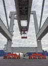 Standing underneath a Container Crane with its Grey Frame and red Painted Wheel Bogeys visible on tracks. Royalty Free Stock Photo