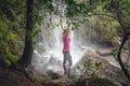 Female standing in waterfalls with lush ferns, trees in bushland Royalty Free Stock Photo