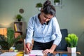Standing Young indian Business woman busy making notes while talking on mobile phone in front of working desk - concept Royalty Free Stock Photo