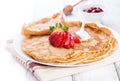 Staple of wheat golden yeast pancakes or crepes, traditional for Russian pancake week, with fresh strawberry on a wooden table