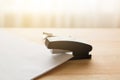 Stapler and staples with sheets of paper on wooden table