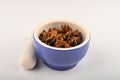 Star anise in a blue ceramic spice mortar with a pestle on a white background. Close up