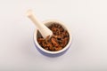 Star anise in a blue ceramic spice mortar with a pestle on a white background. Close up