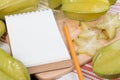 Star apple or averrhoa carambola and notebook on wooden block. Royalty Free Stock Photo