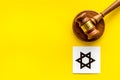 Star of David sign - religion Judaisim symbol - near gavel on yellow table top view. Religious conflict concept. Copy