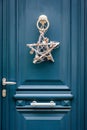 A star-shape Christmas decoration hanging on a blue front door with moldings Royalty Free Stock Photo