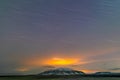 Star trail, clouds and light reflections from the city over the mountain