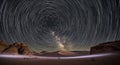 Star trails arch over desert sandstone rock formations in night scene Royalty Free Stock Photo
