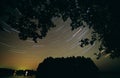 Star trails behind tree branches Royalty Free Stock Photo