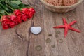 Starfish, heart and red roses on a wooden background