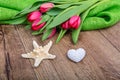 Starfish, heart and tulips on a wooden table