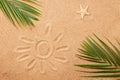 A starfish, palm leaves and a drawing of the sun on the sand on the beach.