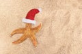 Starfish in red Santa Claus hat on sand. Sunny. Concept for Christmas, New Year at sea, vacation, beach Royalty Free Stock Photo