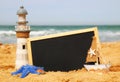 Starfish, sailboat, lighthouse and chalkboard, on sea sand and ocean horizon Royalty Free Stock Photo