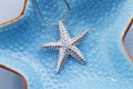 Starfish shape silver pendant necklace on blue background