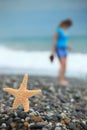 Starfish and young girl on stone seacoast Royalty Free Stock Photo