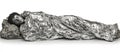 Image of Figure Covered in Crumpled Metallic Blanket, Resting on Rock, Isolated on White Background Royalty Free Stock Photo