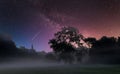 A starry milkyway sky over a misty landscape