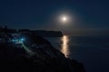 The full moon rises in a starry night sky over the sea and rocky cliffs. The concept of calmness, silence and unity with nature Royalty Free Stock Photo