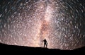 Starry night, silhouette stands on the hill and looking at the colorful star trails on the sky. Night time lapse.