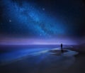 Starry night sky over sea and beach with man silhouette