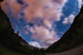 The starry sky with blurred motion colorful clouds and bright moonlight. Expansive night landscape in the European Alps, fisheye u