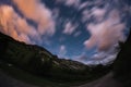 The starry sky with blurred motion colorful clouds and bright moonlight. Expansive night landscape in the European Alps, fisheye u