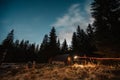 Starry sky with Milky Way and snow covered hut. Rustic old wooden hut in the forest - mountain shelter. Royalty Free Stock Photo