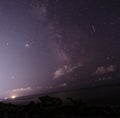 Many different constellations. Starry sky over the sea, the milky way and the lights of the night city. Light in the sky of a Royalty Free Stock Photo