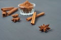 Stars of anise on background of cinnamon sticks near glass bowl full of powder lies on dark scratched desk on kitchen Royalty Free Stock Photo