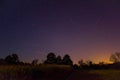 Stars over the forest and village lights in right corner Royalty Free Stock Photo