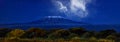 Stars over Mount Kilimajaro. Panoramic, night scenery of snow capped highest african mountain, lit by full moon against deep blue