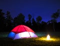 Small camprife and lighted tent at night