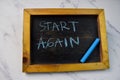 Start Again write on a chalkboard isolated on wooden table
